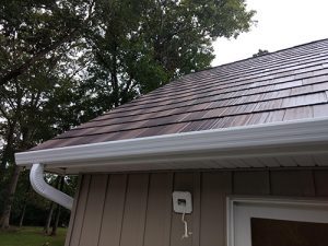 A single-family home with a metal roof has seamless gutters with a gutter protection system.