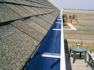 A close-up image of a seamless gutter system installed on a shingle roof.