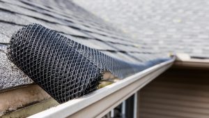 Roll of plastic mesh guard over gutter on a roof to keep it free of leaves, focus on roll of mesh