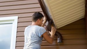 A worker installing Gutter on the Roof of House