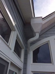 The downspout of a seamless gutter system installed in a house.